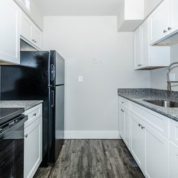 All-electric kitchen with black appliances and white cabinets in a one bedroom apartment at Carlson Apartments, located in Colorado Springs, CO