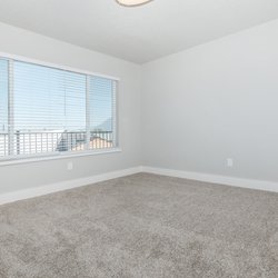 Carpeted bedroom with large windows and ample outlets at Carlson Apartments, located in Colorado Springs, CO